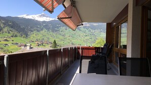 A balcony with a view of a snow-capped mountain and a green valley. - Great Views, Great Location, modern & cozy Apartment (renovated 2022) (Grindelwald)