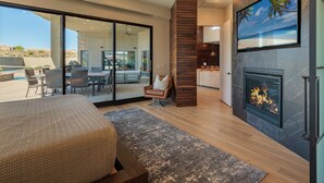 Ein modernes Wohnzimmer mit Kamin, großem Fernseher und Blick ins Freie.