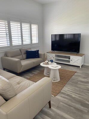 Relax in this stylish living room with a beige sofa, flat-screen TV, and woven rug.