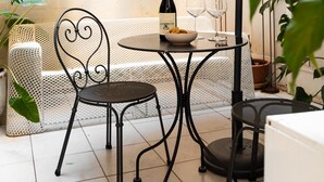 A patio with a round table, two chairs, a bottle of wine, and glasses. - Chic and Style in Historical Via Giulia (Roma)