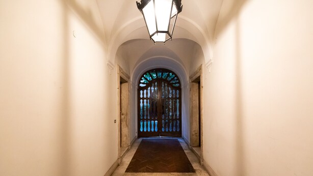 A hallway with a wooden herringbone floor, white walls, and a decorative door with stained glass. - Chic and Style in Historical Via Giulia (Roma)