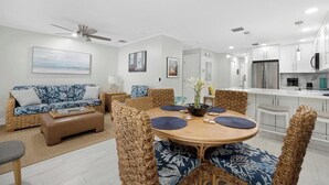 Una sala de estar moderna con una mesa de comedor redonda de madera, sillas de mimbre y un sofá.
