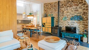 A modern living room with a stone wall, wooden furniture, and a fireplace. - Casa Loris by Wonderful Italy (Olbia)