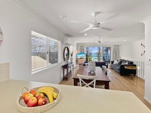 A modern kitchen with a dining area, a ceiling fan, and a view to the outside.