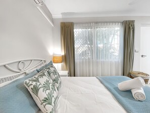 Une chambre d’hôtel avec un lit, des rideaux, une lampe et une vue sur les arbres.
