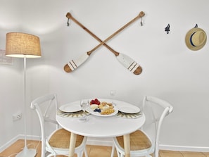 Une table à manger avec des chaises, une lampe et un chapeau accroché au mur.