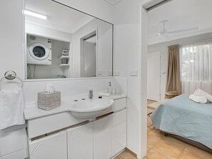 Ein modernes Badezimmer mit Waschbecken, Spiegel und separater Waschbereich.