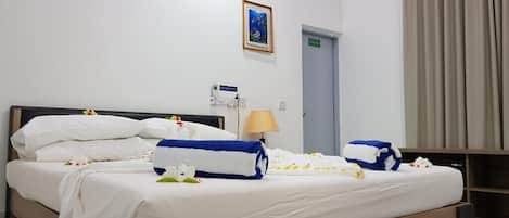 Una habitación de hotel con cama, lámpara de noche, puerta y un cuadro en la pared.