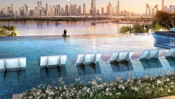 Une piscine avec des chaises longues et, en arrière-plan, la vue sur les gratte-ciel de la ville.