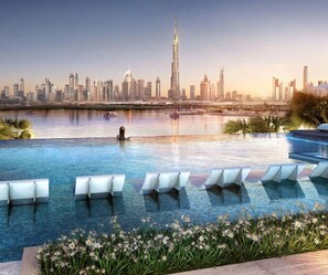 A pool with lounge chairs and a city skyline in the background. - Lux BnB The Grand Creek Harbor Views (Dubai)