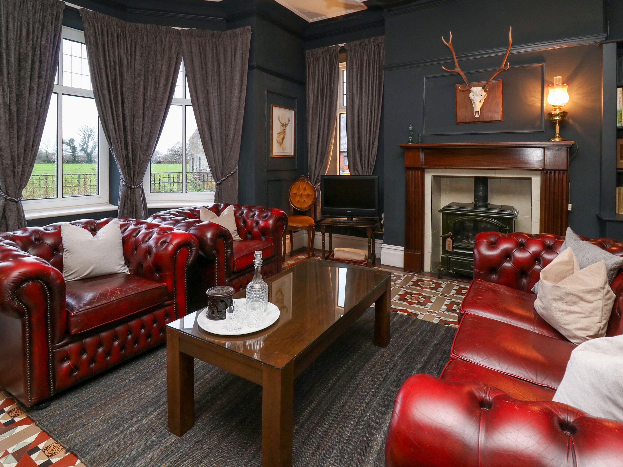 A room with a red leather sofa set, a wooden coffee table, a fireplace, and a television.