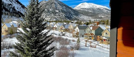 Overlooking a serene mountain range, this room offers breathtaking views of snow-covered homes and a coniferous tree.