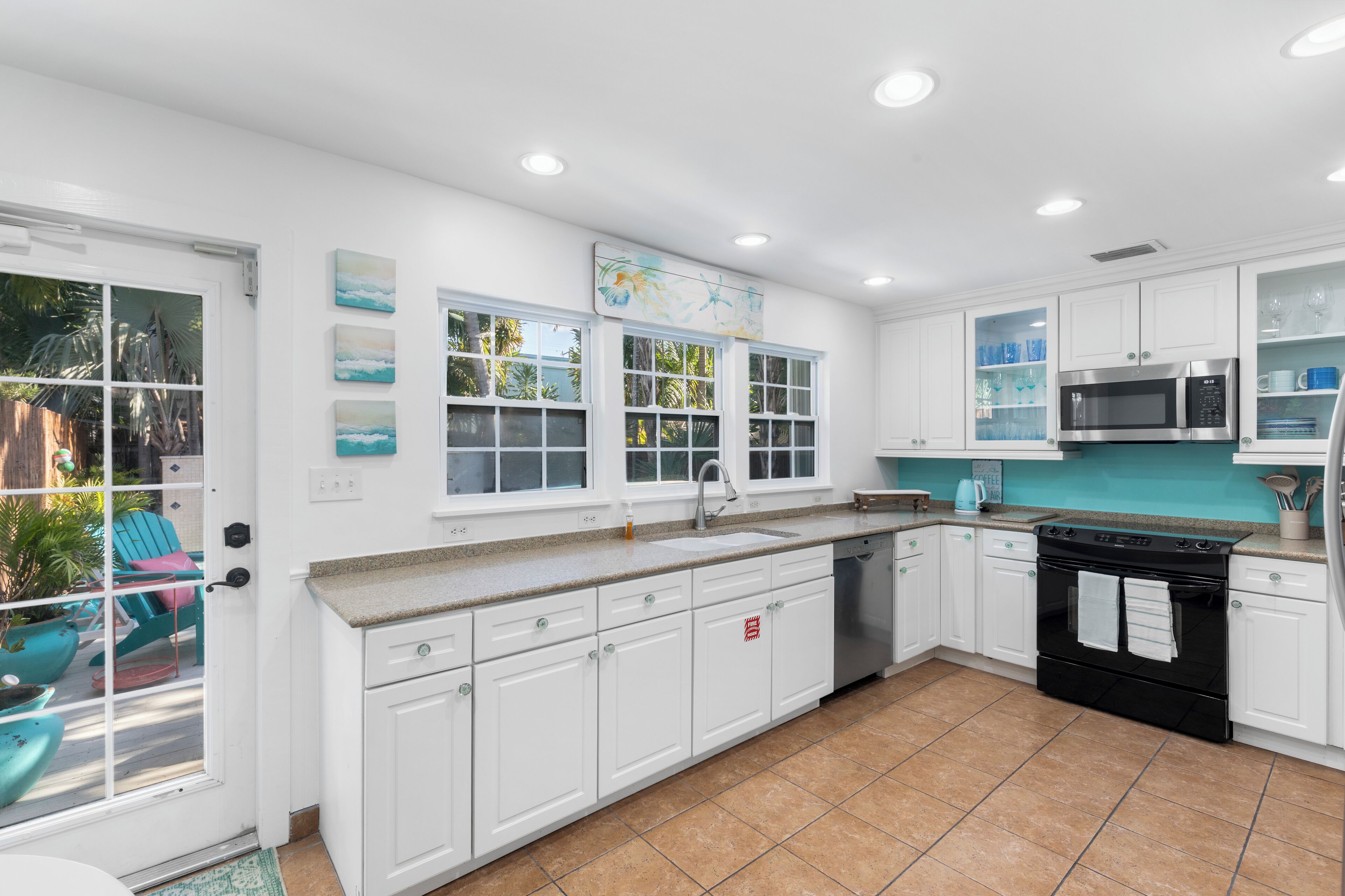 A kitchen with white cabinets, a black stove, and a microwave.