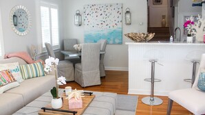 A modern living room with a sofa, chairs, a coffee table with a plant, and a dining area with a table and chairs.
