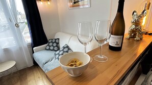 Un salon chaleureux avec une table en bois, deux verres à vin, un bol de nourriture et une bouteille de vin.