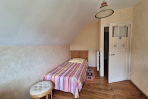 Ein Schlafzimmer mit einem Einzelbett, einem Sessel, einer Tür und einem Heizkörper.