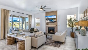 A modern living room with a sofa, armchairs, a fireplace, and a television.