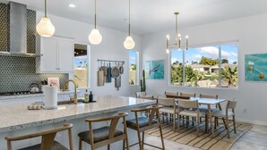 A modern kitchen with a large island, bar stools, and a dining area with a view of the outdoors.