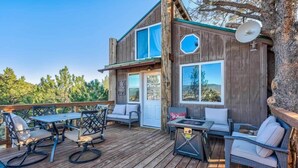 A wooden deck with outdoor furniture, a satellite dish, and a door. - Heavenly Haven Treehouse (Larkspur)