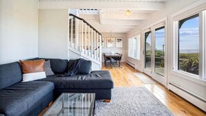 Ein modernes Wohnzimmer mit einem Ecksofa, einem Glastisch und einer Treppe, die in ein Obergeschoss führt.
