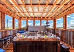 Eine Holzhütte mit Whirlpool, großen Fenstern und Blick auf die Landschaft.