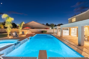 Piscina con escalones, mobiliario de exterior y un área cubierta con sombrillas.