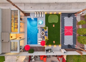 A modern outdoor pool area with a hot tub, lounge chairs, and a tennis court. - The Cardinal | Ultimate Group Retreat in Glendale (Glendale)