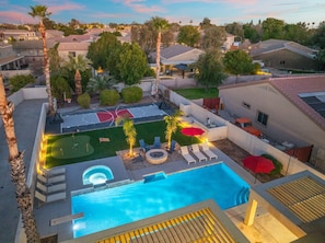 A residential area with a swimming pool, outdoor seating, and a basketball court.