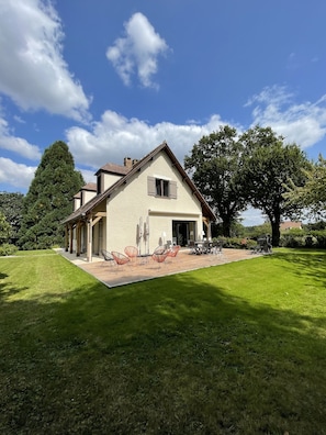 Een twee verdiepingen tellend huis met een overdekte patio en een zitgedeelte buiten.