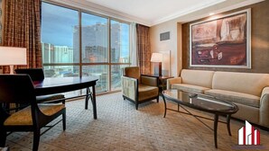 A spacious living room with a large window, a dining area, and a sofa. - MGM Signature-Strip View Jacuzzi Studio Work Desk (Las Vegas)