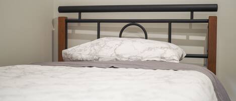 A bed with a headboard, a pillow, and a blanket.