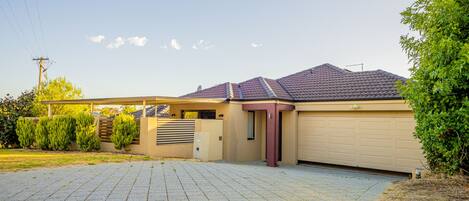A residential garage with a covered driveway and a well-maintained lawn.