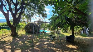A garden with a swing set, a small pond, and a large tree. - CHARMING HOUSE WITH PRIVATE POOL (Prunelli-di-Fiumorbo)