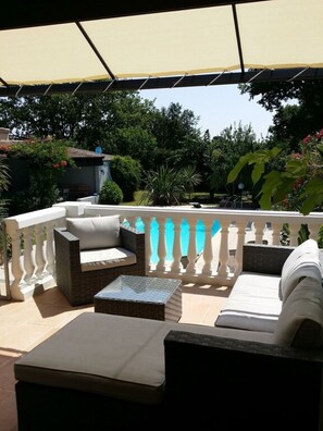 An outdoor patio with a covered seating area, including a sofa and two armchairs, surrounded by a white balustrade. - Charming House with a Private Pool (Prunelli-di-Fiumorbo)
