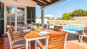 An outdoor dining area with a pool in the background.