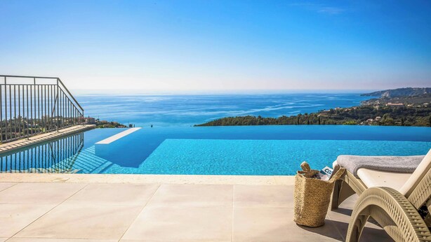 An infinity pool with a clear view of the sea and a distant island.
