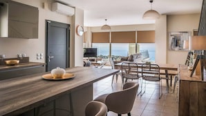 A modern kitchen with a wooden countertop, a dining area with a table and chairs, and a large window offering a view of the outdoors.