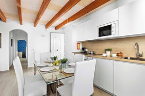 Une cuisine moderne avec des meubles blancs, un four à micro-ondes et un plan de travail en bois.