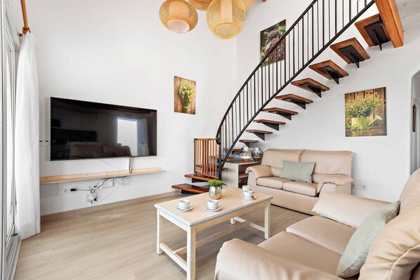 Una sala de estar moderna con una escalera curva, un televisor de pantalla plana, un sofá y una mesa de centro.