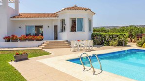 Una casa moderna con piscina, mobiliario exterior y jardín.