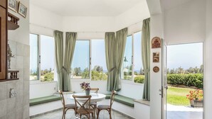 Una habitación luminosa con una mesa de comedor, sillas y vistas a zonas verdes.