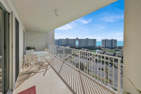 A balcony with a table and chairs, overlooking a marina with high-rise buildings and a clear sky.