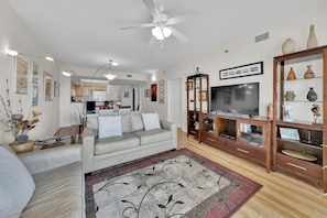 A living room with a sofa, a TV, a wooden cabinet, and a ceiling fan.
