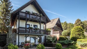 A two-story chalet with a balcony, surrounded by a well-maintained lawn and garden. - Apartment Bellevue in a chalet on Lake Sader (Buckow (Märkische Schweiz))