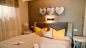 A neatly made bed with a white comforter and pillows, a bedside table with a lamp, and a wall-mounted artwork above the bed. - Apartment Bellevue in a chalet on Lake Sader (Buckow (Märkische Schweiz))