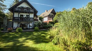 A two-story house with a balcony, a garden, and a neighboring building. - Apartment Bellevue in a chalet on Lake Sader (Buckow (Märkische Schweiz))