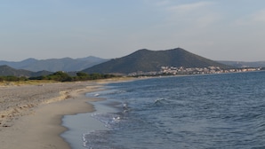 A beach with a mountain in the background and a town across the water.