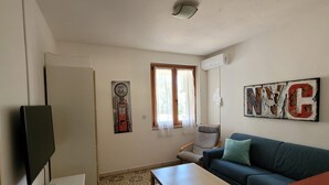 A living room with a TV, sofa, coffee table, patterned floor, and a wall with 'NYC' letters.