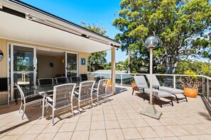 Eine überdachte Terrasse mit Sitzgelegenheit, einem Tisch mit Stühlen und einem Blumentopf.