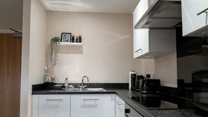 A modern kitchen with white cabinets, a black countertop, and a stainless steel range hood. - Modern & Spacious 1 Bed Apartment in Manchester (Salford)